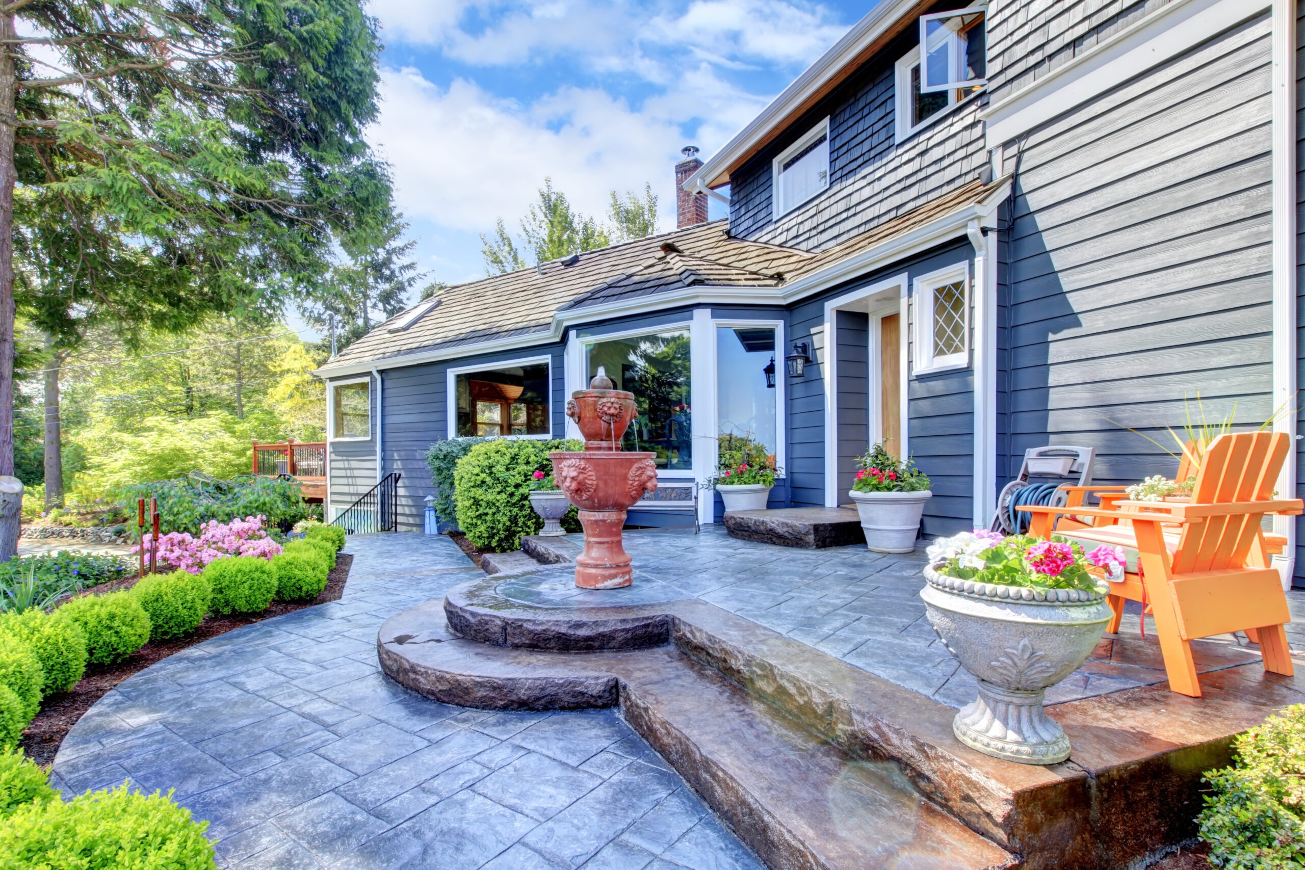 Blue house with nice new patio and fountain with flowers.